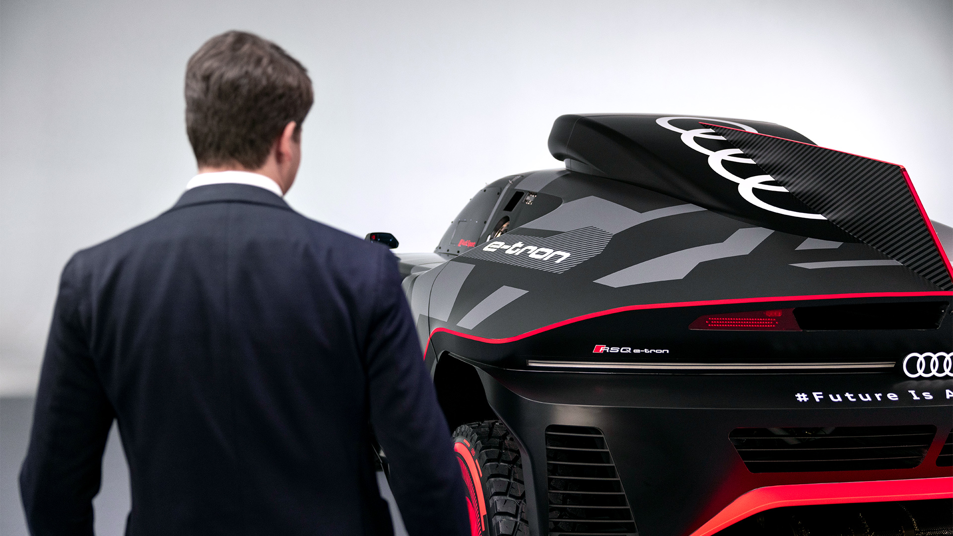 Julius Seebach standing with his back to the camera, to the left of the Audi RS Q e-tron{ft_rs-q-e-tron}.