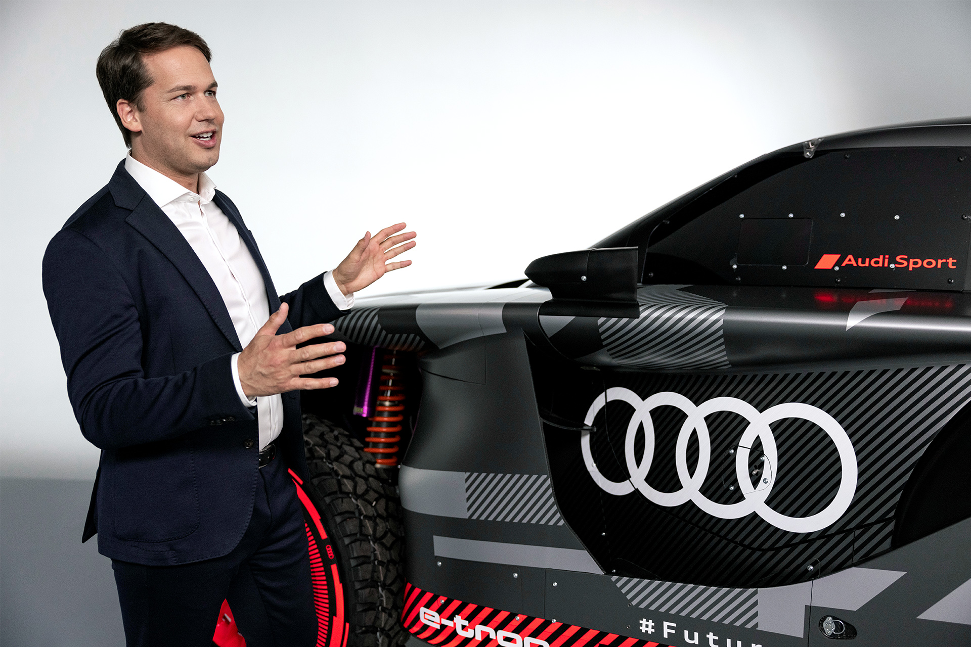 Julius Seebach standing next to the Audi RS Q e-tron, gesticulating with his hands.