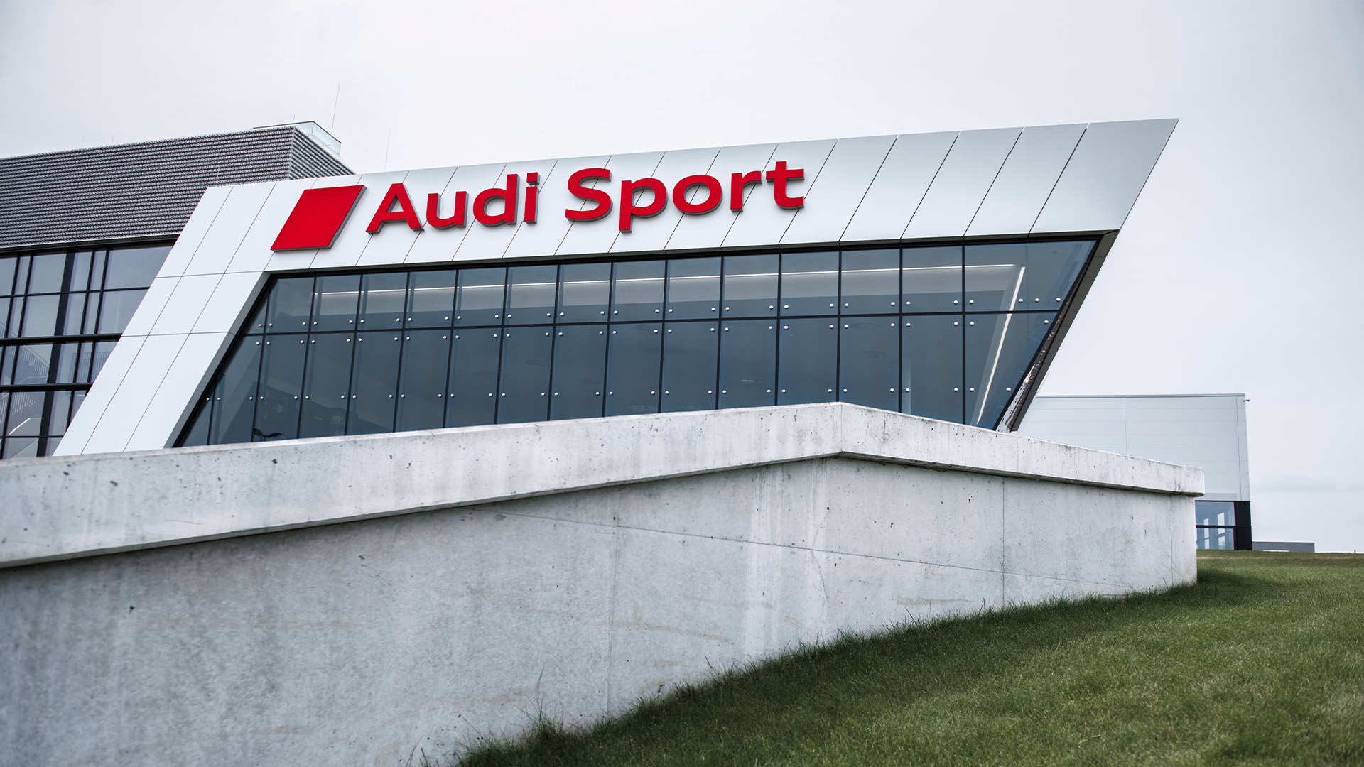 The Audi Sport building can be seen behind a small wall.