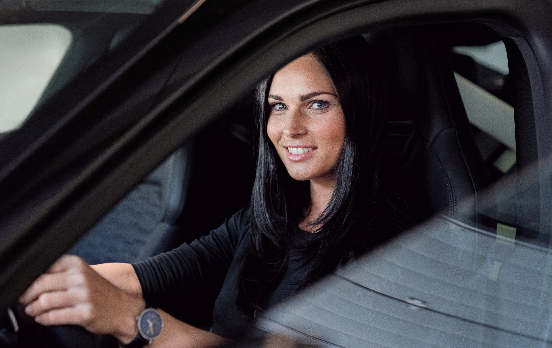 Anna Veith sits at the steering wheel in the Audi e-tron GT{ft_e-tron-gt} and looks into the camera.