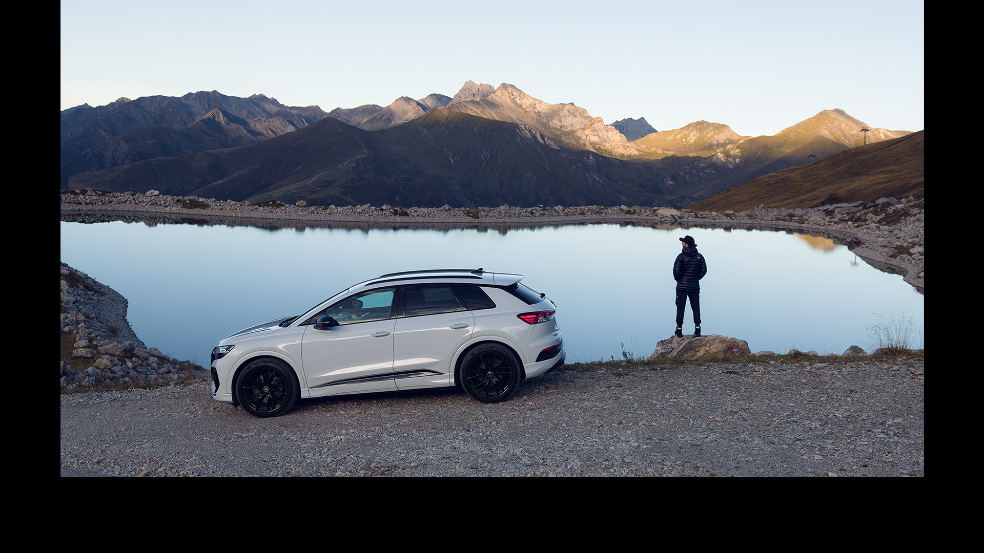 A white Audi Q4 e-tron stands in front of a lake.