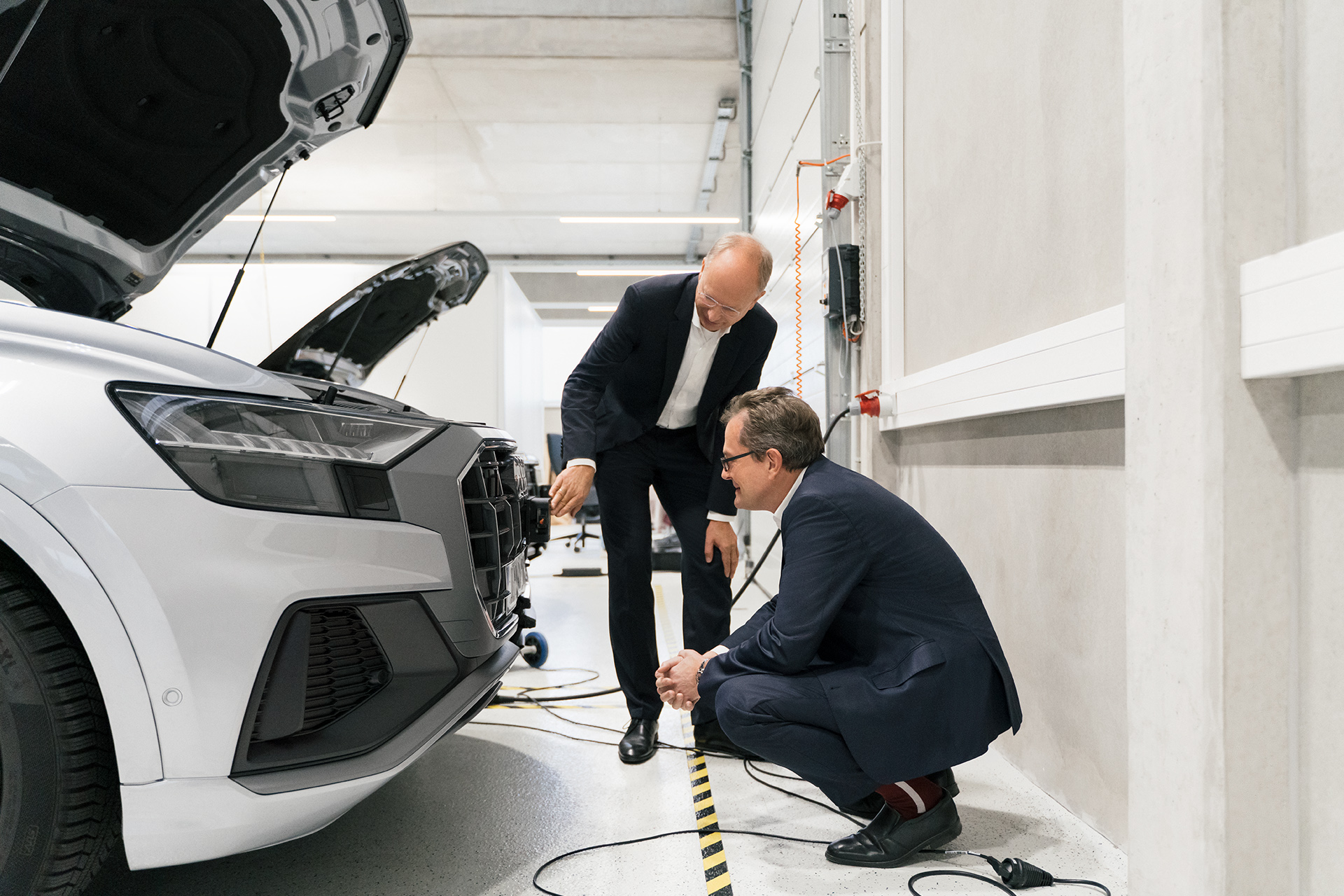 Prof. Christoph Lütge, Dr. Thomas Dahlem and Dr. Essayed Bouzouraa discuss sensor technology at the front end of an Audi model